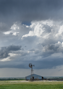 Storm building over barn and windmill